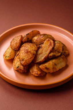 Baharatlı, sarımsaklı ve biberiyeli patates dilimleri. Tasarımınız için yemek arkaplanı olarak patates dilimleri