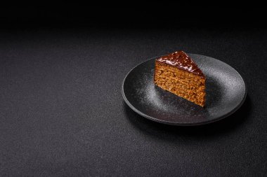 A slice of sweet layered cake covered in chocolate with nuts and caramel. A slice of chocolate cake as a food background for your design.