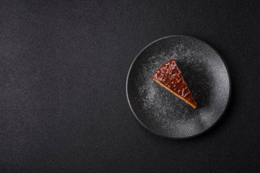 A slice of sweet layered cake covered in chocolate with nuts and caramel. A slice of chocolate cake as a food background for your design.