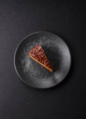 A slice of sweet layered cake covered in chocolate with nuts and caramel. A slice of chocolate cake as a food background for your design.