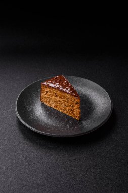 A slice of sweet layered cake covered in chocolate with nuts and caramel. A slice of chocolate cake as a food background for your design.