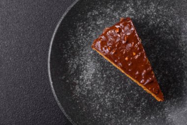 A slice of sweet layered cake covered in chocolate with nuts and caramel. A slice of chocolate cake as a food background for your design.