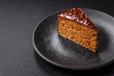 A slice of sweet layered cake covered in chocolate with nuts and caramel. A slice of chocolate cake as a food background for your design.