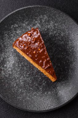 A slice of sweet layered cake covered in chocolate with nuts and caramel. A slice of chocolate cake as a food background for your design.