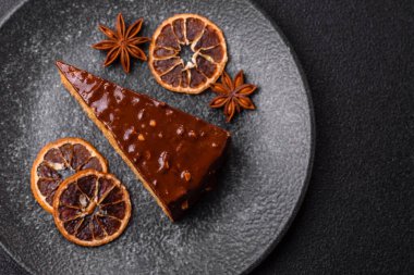 A slice of sweet layered cake covered in chocolate with nuts and caramel. A slice of chocolate cake as a food background for your design.