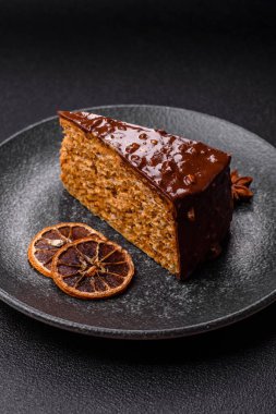 A slice of sweet layered cake covered in chocolate with nuts and caramel. A slice of chocolate cake as a food background for your design.