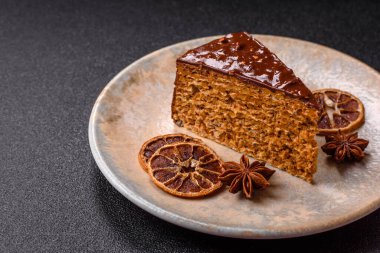 A slice of sweet layered cake covered in chocolate with nuts and caramel. A slice of chocolate cake as a food background for your design.