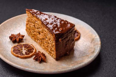 A slice of sweet layered cake covered in chocolate with nuts and caramel. A slice of chocolate cake as a food background for your design.