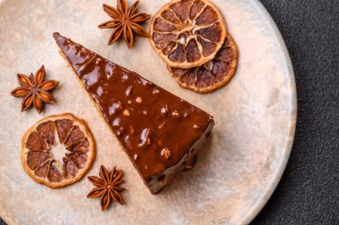 A slice of sweet layered cake covered in chocolate with nuts and caramel. A slice of chocolate cake as a food background for your design.