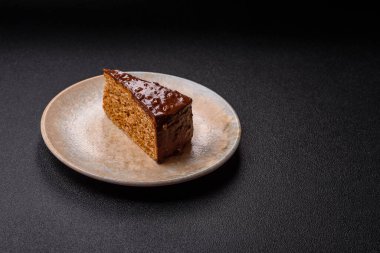 A slice of sweet layered cake covered in chocolate with nuts and caramel. A slice of chocolate cake as a food background for your design.