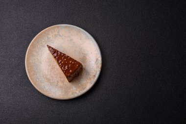 A slice of sweet layered cake covered in chocolate with nuts and caramel. A slice of chocolate cake as a food background for your design.