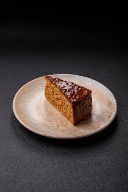 A slice of sweet layered cake covered in chocolate with nuts and caramel. A slice of chocolate cake as a food background for your design.