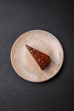A slice of sweet layered cake covered in chocolate with nuts and caramel. A slice of chocolate cake as a food background for your design.