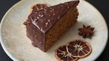 A slice of sweet layered cake covered in chocolate with nuts and caramel. A slice of chocolate cake