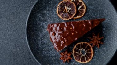 A slice of sweet layered cake covered in chocolate with nuts and caramel. A slice of chocolate cake