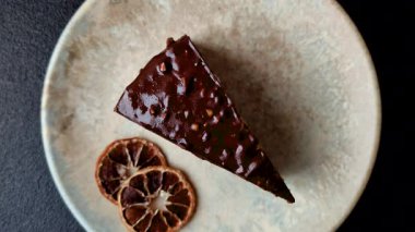 A slice of sweet layered cake covered in chocolate with nuts and caramel. A slice of chocolate cake