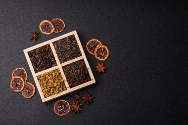 A wooden box with several types of dried tea, green, black, fruit, and chamomile. Dry tea in the box as a backdrop for your design.