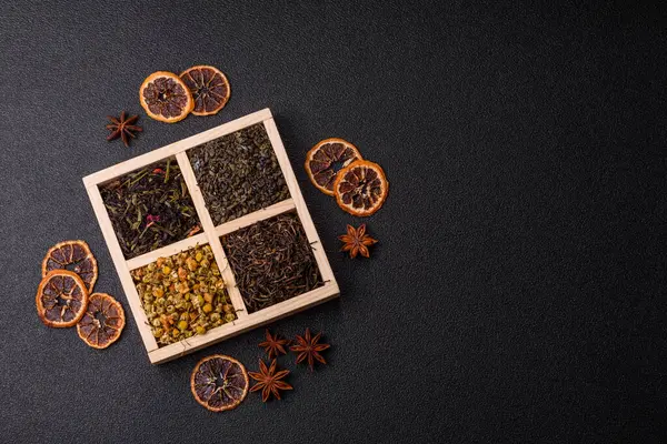 A wooden box with several types of dried tea, green, black, fruit, and chamomile. Dry tea in the box as a backdrop for your design.