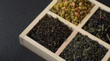 A wooden box with several types of dried tea, green, black, fruit, and chamomile. Dry tea in the box as a backdrop for your design.