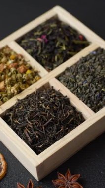A wooden box with several types of dried tea, green, black, fruit, and chamomile. Dry tea in the box as a backdrop for your design.
