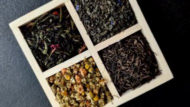 A wooden box with several types of dried tea, green, black, fruit, and chamomile. Dry tea in the box as a backdrop for your design.
