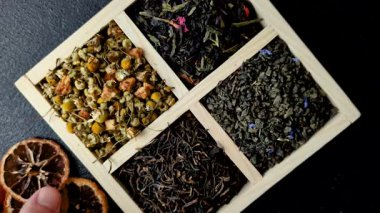 A wooden box with several types of dried tea, green, black, fruit, and chamomile. Dry tea in the box as a backdrop for your design.