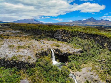 Cotopaxi 'de doğan ve volkanik kayalardaki bir kanaldan geçen kristal sudan oluşan şelale.