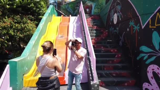 コロンビアのメデリン2022年コムナ13スラム かつて世界で最も危険な地域の1つ サンサルヴァトーレ地区 南米の貧しい人々のための貧しい家庭 カラフルなスライドや観光客 — ストック動画