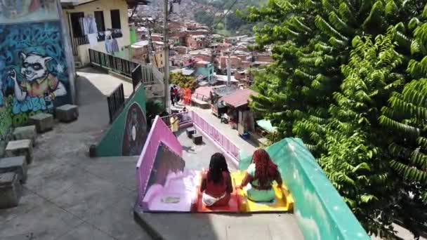 コロンビアのメデリン2022年コムナ13スラム かつて世界で最も危険な地域の1つ サンサルヴァトーレ地区 南米の貧しい人々のための貧しい家庭 カラフルなスライドや観光客 — ストック動画