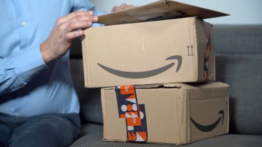 Europe, Italy , Milan January 2023 - unboxing of Amazon delivery pack -  home delivery and home opening on sofa