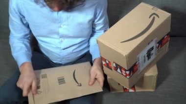 Europe, Italy , Milan January 2023 - unboxing of Amazon delivery pack -  home delivery and home opening on sofa