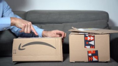 Europe, Italy , Milan January 2023 - unboxing of Amazon delivery pack -  home delivery and home opening on sofa