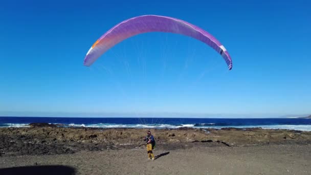 スペイン ランサローテ ファマラビーチ パラグライダーは存在下で無料のフライトの最も簡単で軽量な手段です 男は海のビーチで風を待つ — ストック動画