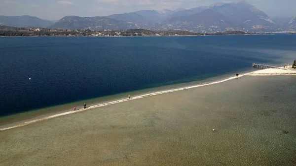 stock image Italy, Lake Garda ,San Biagio Island , Rabbit Island - the shallow waters of the lake allow you to walk and reach the island on foot - water emergency in Lombardy , drought lowering of the water level