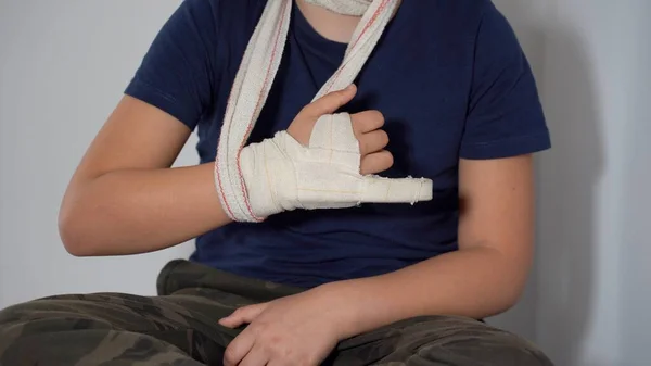 boy child 8 years old child breaks by fracturing the finger of his right hand and wears a rigid plaster bandage to heal the fracture - lifestyle in an apartment after a typical childhood injury