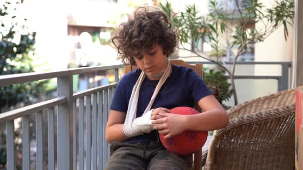 男の子8歳の子供は右手の指を骨折し 骨折を癒すために硬い石膏の包帯を身に着けています 典型的な小児期の怪我の後のアパートでの生活 — ストック動画