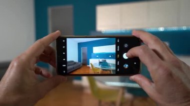  Milano Man profesyonel fotoğrafçı gayrimenkul satışa çıkarılmış evlerin cep telefonlarıyla video ve fotoğraf çekiyor. Mutfak mavi duvarlı oturma odasında sahneleniyor. 