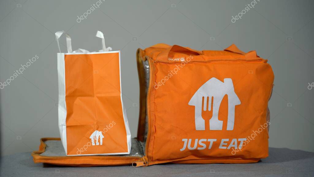 Europe, Italy, Milan 2023 - Just Eat food delivery arrives home in the apartment where the man is ready for dinner - home delivery on the landing outside the door
