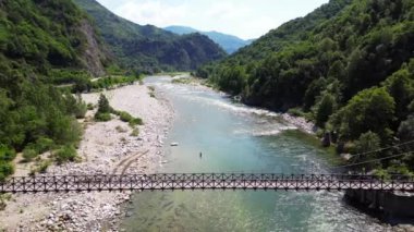 Alagna Val Sesia Piedmont Alp Dağları 'ndaki insansız hava aracının görüntüsü ile nehir kıyılarına katılan tahta Tibet asma köprüsünün üzerinden insansız hava aracı uçuşu macera yolculuğunda konsept yolculuk.