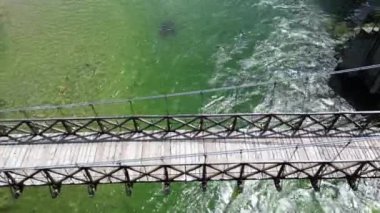 Alagna Val Sesia Piedmont Alp Dağları 'ndaki insansız hava aracının görüntüsü ile nehir kıyılarına katılan tahta Tibet asma köprüsünün üzerinden insansız hava aracı uçuşu macera yolculuğunda konsept yolculuk.