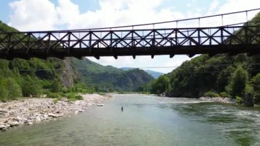 Alagna Val Sesia Piedmont Alp Dağları 'ndaki insansız hava aracının görüntüsü ile nehir kıyılarına katılan tahta Tibet asma köprüsünün üzerinden insansız hava aracı uçuşu macera yolculuğunda konsept yolculuk.