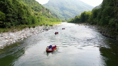 Val Sesia Alagna Piedmont Alpleri 'ndeki kanyonun doğası ve derenin akıntısına batmış botlarla nehirde rafting yapmak yaz su sporları aktivitelerinin insansız hava aracı görüntüsüdür.