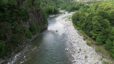 Val Sesia Alagna Piedmont Alpleri 'ndeki kanyonun doğası ve derenin akıntısına batmış botlarla nehirde rafting yapmak yaz su sporları aktivitelerinin insansız hava aracı görüntüsüdür.