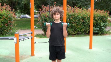 İtalya, Milan - Erkek çocuk 9 yaşında. Ağırlık ekipman alanı olan bir parkta jimnastik yapıyor. Spor aktiviteleri ve yaz hazırlama diyeti yapıyor.