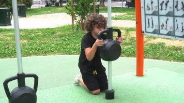 İtalya, Milan - Erkek çocuk 9 yaşında. Ağırlık ekipman alanı olan bir parkta jimnastik yapıyor. Spor aktiviteleri ve yaz hazırlama diyeti yapıyor.