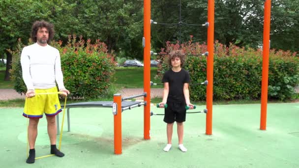 イタリア ミラノ 男の子の子供9歳は 体重機器エリアのある公園で体操ジムを行います 体操スポーツ活動と夏の準備食事 子供の頃のスポーツ — ストック動画