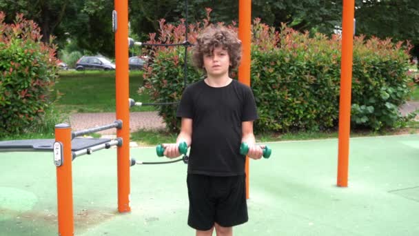 イタリア ミラノ 男の子の子供9歳は 体重機器エリアのある公園で体操ジムを行います 体操スポーツ活動と夏の準備食事 子供の頃のスポーツ — ストック動画