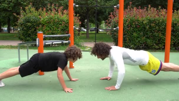 イタリア ミラノ 父と息子の子供9歳は重量機器エリアのある公園で体操ジムを行う 身体運動スポーツ活動と夏の準備食事 — ストック動画