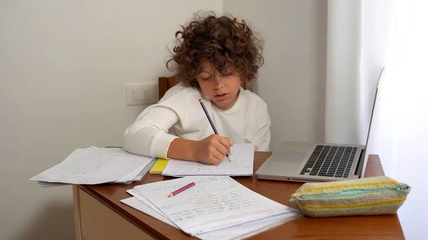 9歳の小学生の男の子が宿題をする 夏休みのために学校で与えられた数学の練習をする コンピュータラップトップで子供時代のライフスタイルの学生 — ストック写真