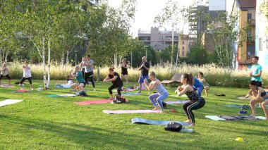 Avrupa, İtalya, Milano 06-20-2023 - insanlar Bam Giardino degli Alberi Garibaldi 'de bir parkta yoga meditasyon dersi veriyor - yaz tatillerinde jimnastik ve spor aktiviteleri ve diyet yapıyorlar